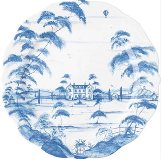 A scalloped ceramic plate featuring a classic blue and white chinoiserie landscape print with a chateau, trees, and a hot air balloon.
